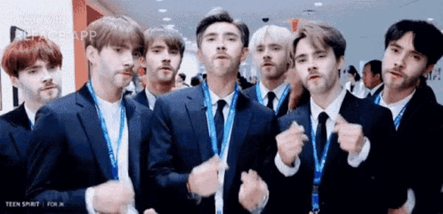 a group of young men in suits and ties are standing next to each other .
