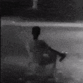 a black and white photo of a person walking on a sidewalk .