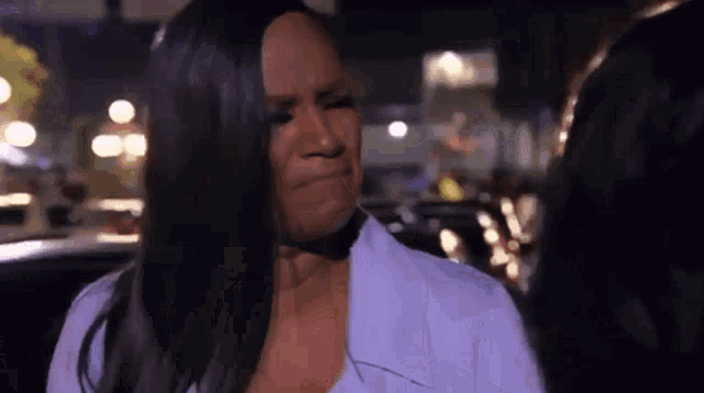 a woman is crying while standing next to another woman in a car at night .