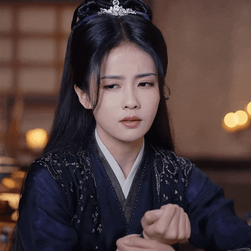 a woman with a tiara on her head is wearing a blue kimono
