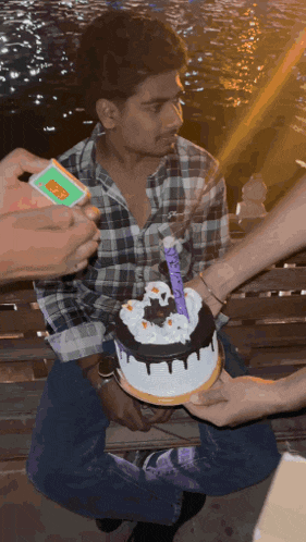 a man in a plaid shirt is holding a birthday cake with a candle that says " happy birthday "