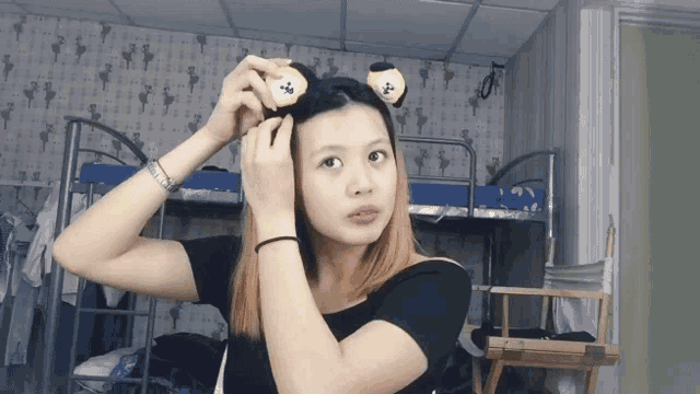 a girl wearing a headband with ears on it is standing in front of a bunk bed