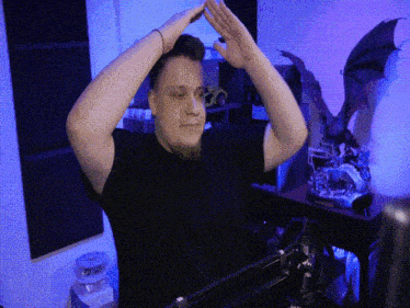 a man in a black shirt holds his hands up in the air