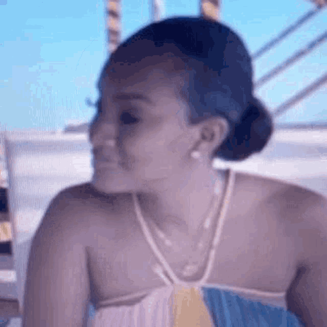 a woman wearing a necklace and a bun is sitting on a boat .