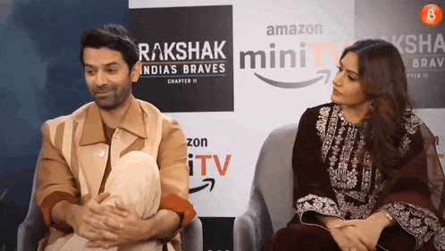 a man and a woman are sitting in front of an amazon mini tv sign