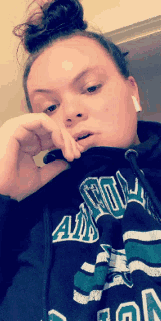 a woman wearing a hoodie that says a&m on it smoking a cigarette