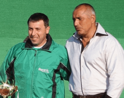 two men standing next to each other one of whom is wearing a green jacket that says spago on it