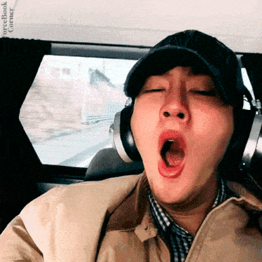 a man wearing headphones is yawning in a car