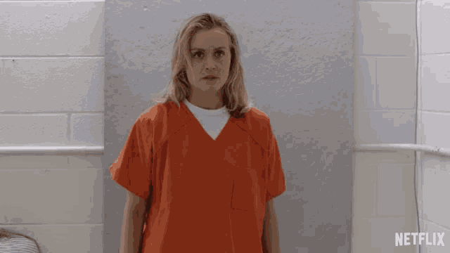 a woman in an orange jumpsuit is standing in front of a netflix ad