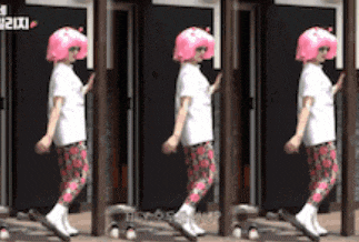 a woman wearing a pink wig and floral pants is walking
