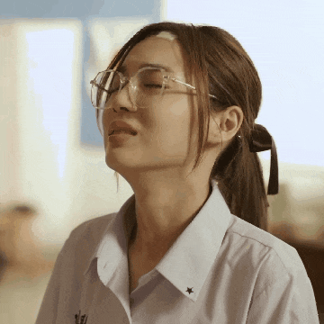 a woman wearing glasses and a white shirt with a star on the collar has her eyes closed