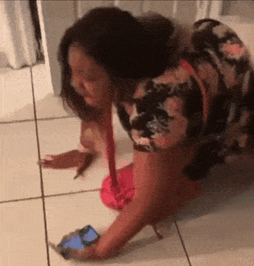 a woman in a floral dress is laying on the floor with a phone in her hand