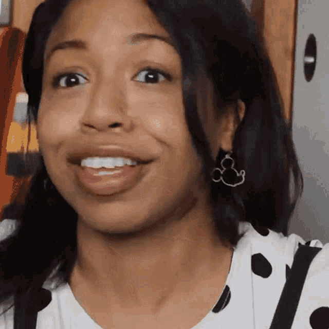 a woman wearing mickey mouse earrings is smiling .
