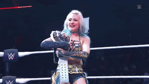 a woman in a wrestling ring is holding a trophy