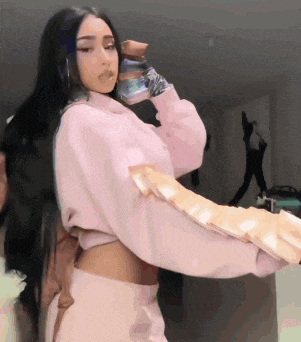a woman in a pink sweater is holding a bottle of water in her hand