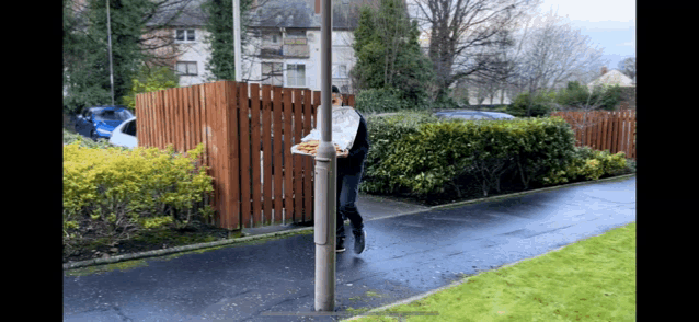 a man carrying a tray of food is walking down a sidewalk