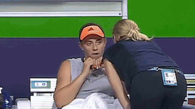 a woman wearing an orange adidas hat is being helped by a nurse