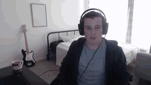 a man wearing headphones is sitting in front of a guitar