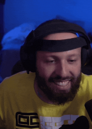 a man with a beard wearing headphones and a yellow shirt with the letter g on the front