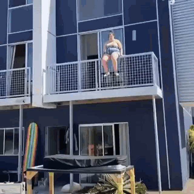 a man is sitting on the balcony of a building .