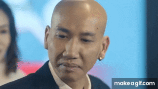 a bald man in a suit and white shirt is making a funny face