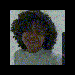 a woman with curly hair is smiling and taking a selfie with her phone .