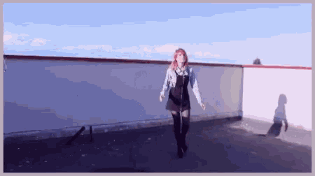 a girl with red hair is dancing on a rooftop