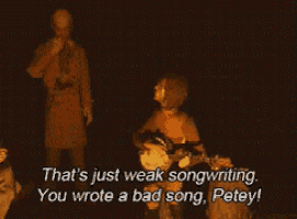 a man is singing into a microphone while a woman plays a guitar and says that 's just weak songwriting