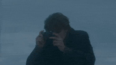 a close up of a young man 's face wearing a sweater against a cloudy sky .
