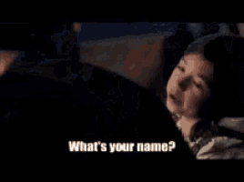 a man in a suit is talking to a woman and asking her what 's her name .
