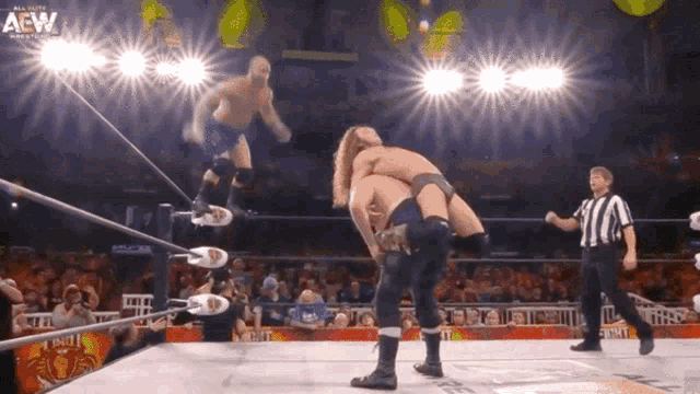a wrestler is jumping over another wrestler in a ring that says aew on the bottom