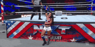 a woman stands in a wrestling ring in front of a banner that says nxt