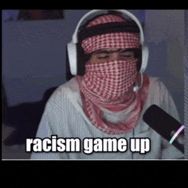 a man wearing headphones and a scarf around his face has the words racism game up above him
