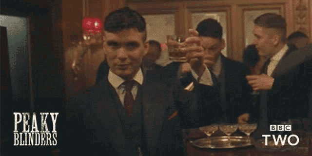 a man in a suit drinking from a glass with peaky blinders on the bottom