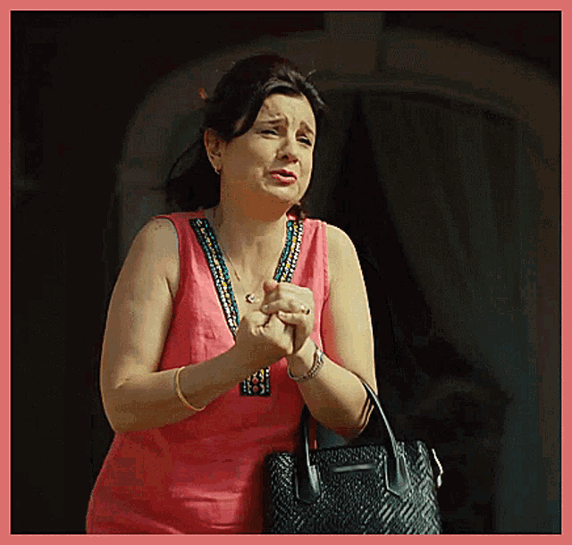 a woman in a pink tank top is holding a black bag