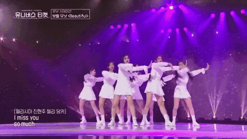 a group of women are dancing on a stage with purple lights and the words i miss you so much on the bottom