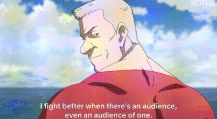 a man in a red shirt is standing in front of the ocean and talking to someone .