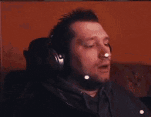 a man is holding his hands up in the air while wearing headphones and making a funny face .