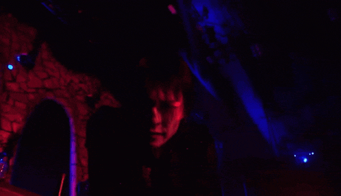 a person in a dark room with red lights behind them
