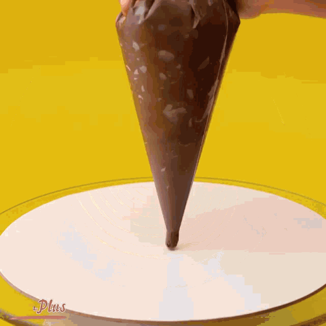 a person spreading chocolate icing on a white plate