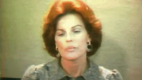 a woman with red hair and earrings looks at the camera