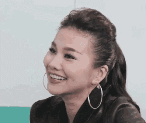 a close up of a woman wearing hoop earrings and a ponytail smiling .
