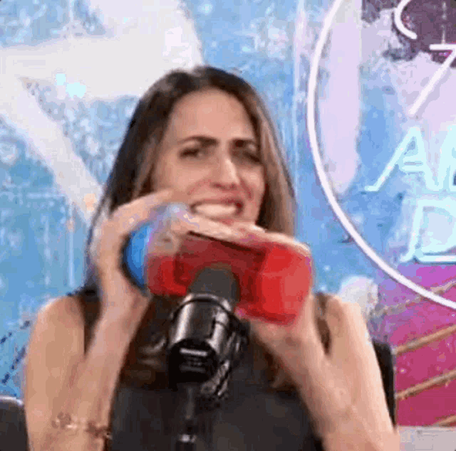 a woman is holding a red bottle in front of a microphone .