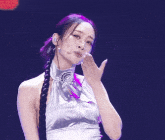 a woman in a silver dress with a braided ponytail is dancing on a stage