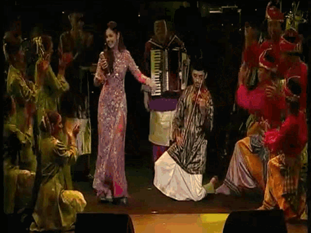a woman in a pink dress is singing on stage