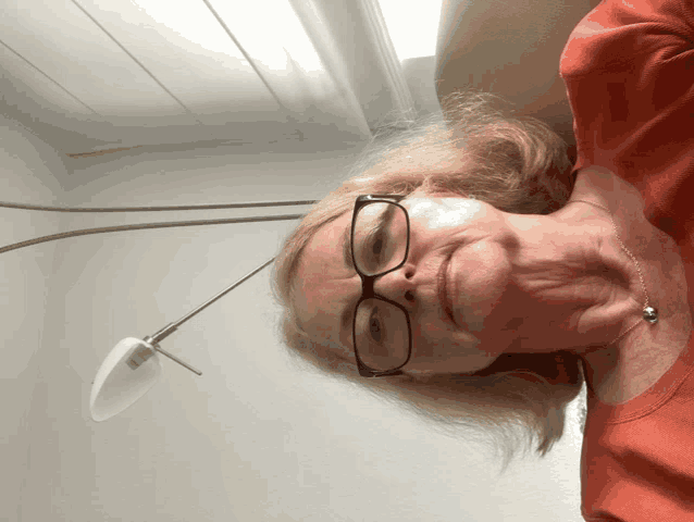 a woman wearing glasses and an orange shirt is laying down