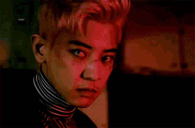 a close up of a man 's face with pink hair and a striped turtleneck .