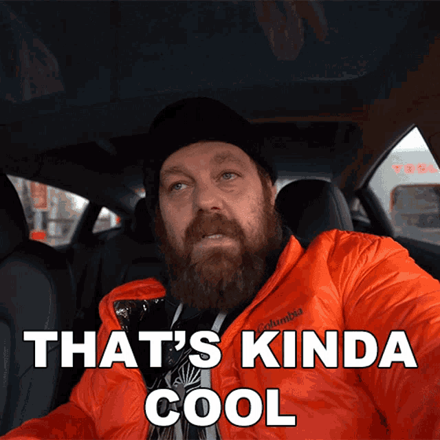 a man with a beard is sitting in a car with the words that 's kinda cool above him