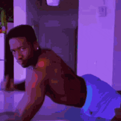 a shirtless man in blue shorts is doing push ups