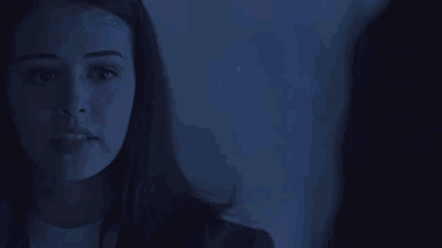 a woman is looking at her reflection in a mirror in a dark room .
